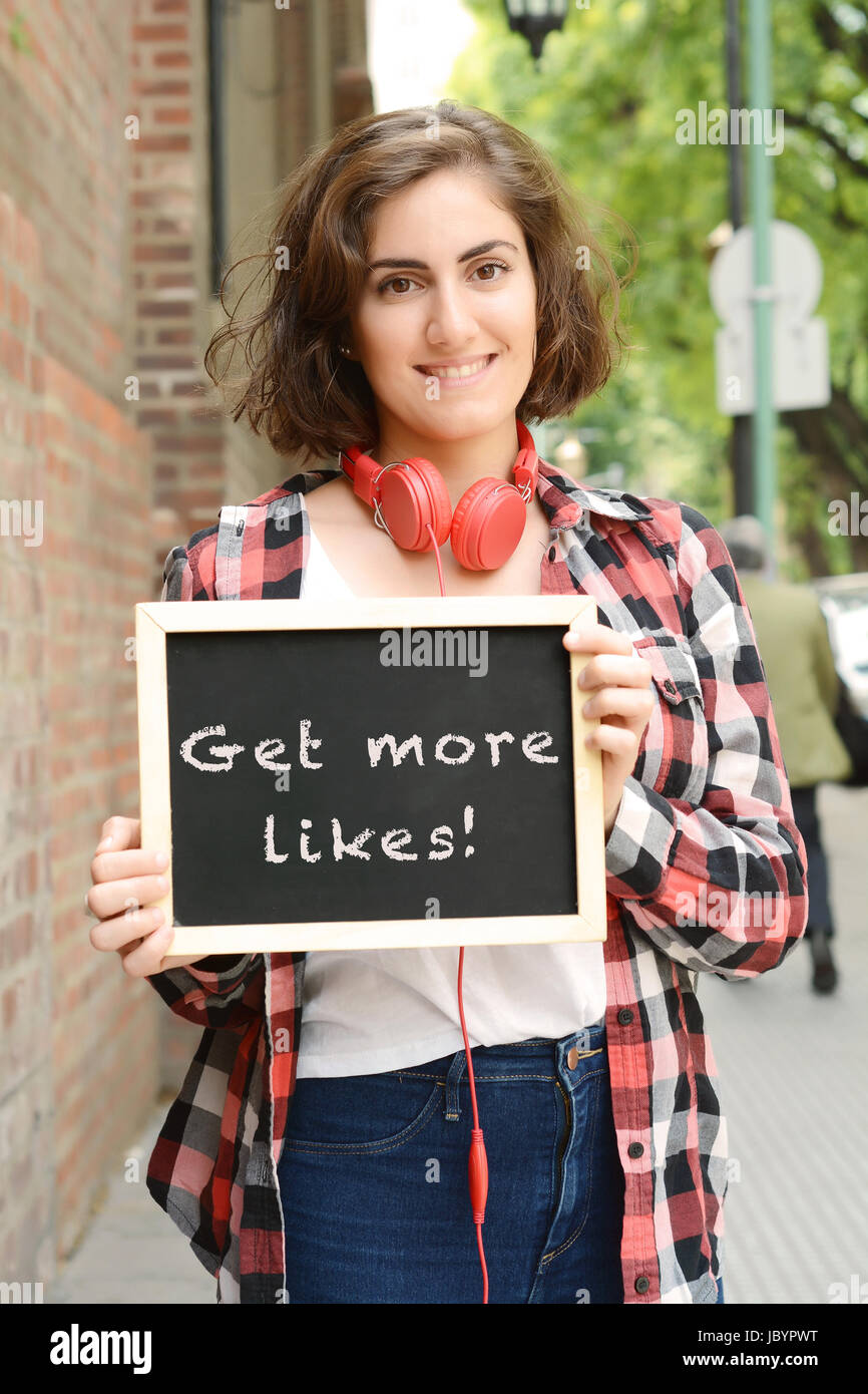 Junge schöne Frau mit Tafel mit Text "erhalten Sie mehr likes". Social-Media-Konzept. Im Freien. Stockfoto
