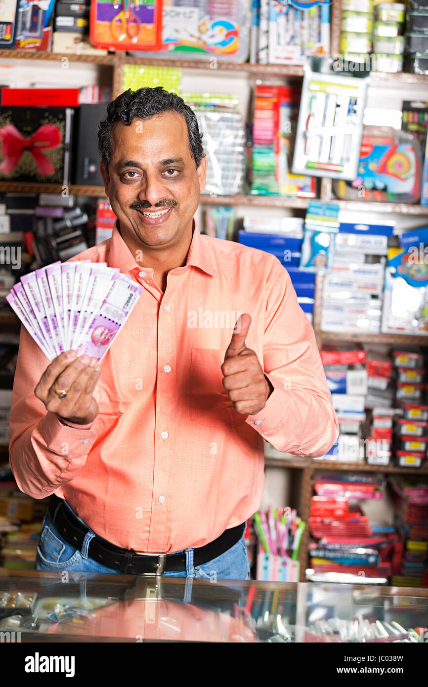 1 Indischer Ladenbesitzer Mann mit Daumen hoch mit Geld Bargeld in stationären Shop Stockfoto