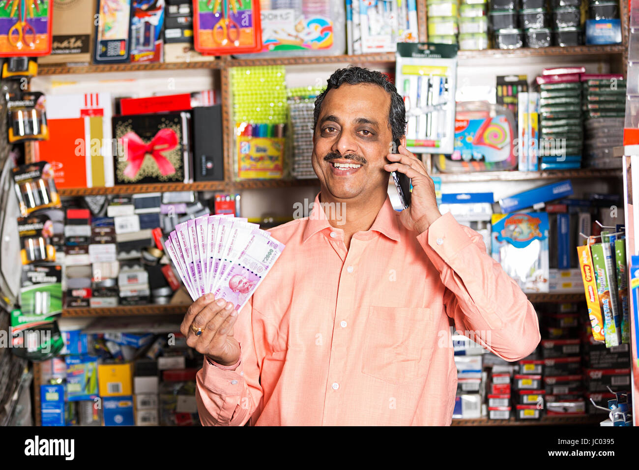 1 Indischer Ladenbesitzer Mann mit Geld Rupien und Sprechen Telefon In stationären Shop Stockfoto