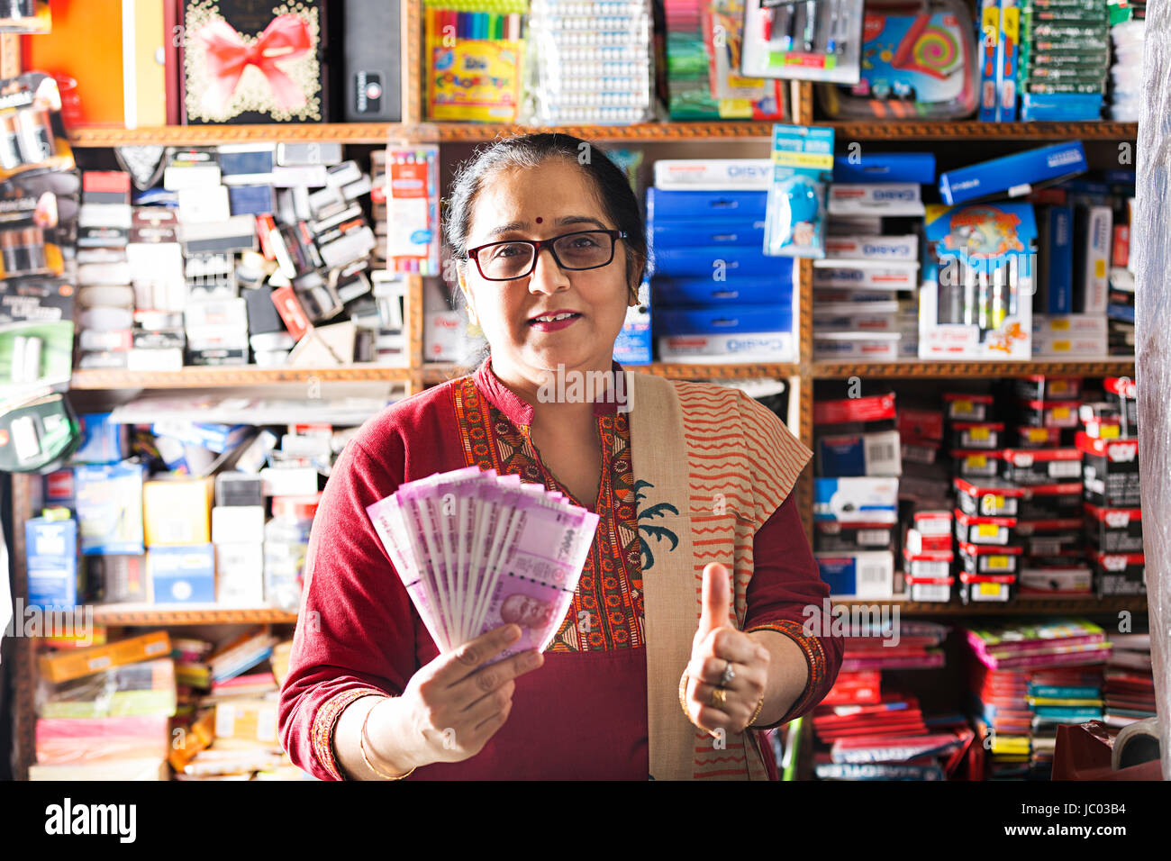 1 Indischer Ladenbesitzer Frau Daumen nach oben zeigt mit Geld Rupien in stationären Shop Stockfoto