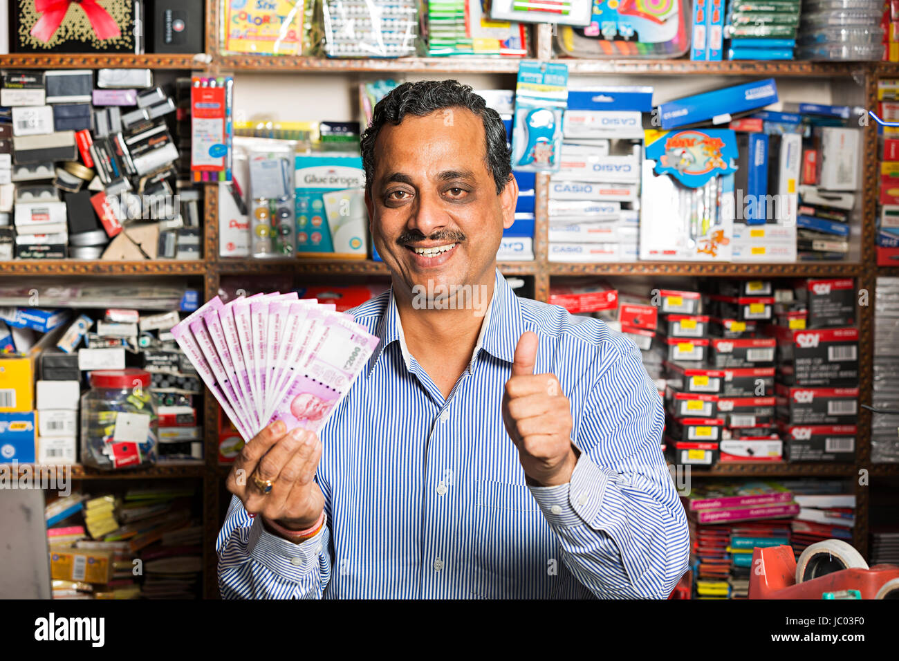 1 Indischer Ladenbesitzer Mann Daumen nach oben zeigt mit Geld Rupien in stationären Shop Stockfoto