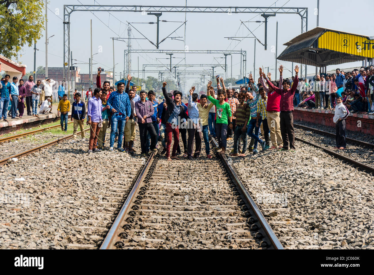 Einige Männer blockieren Bahnstrecke zu einem ländlichen Bahnhof Stockfoto
