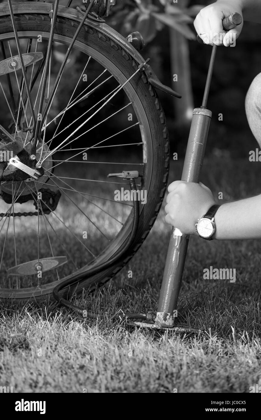 Closeup schwarz-weiß Foto des jungen Mannes Fahrradreifen mit Handpumpe Pumpen Stockfoto