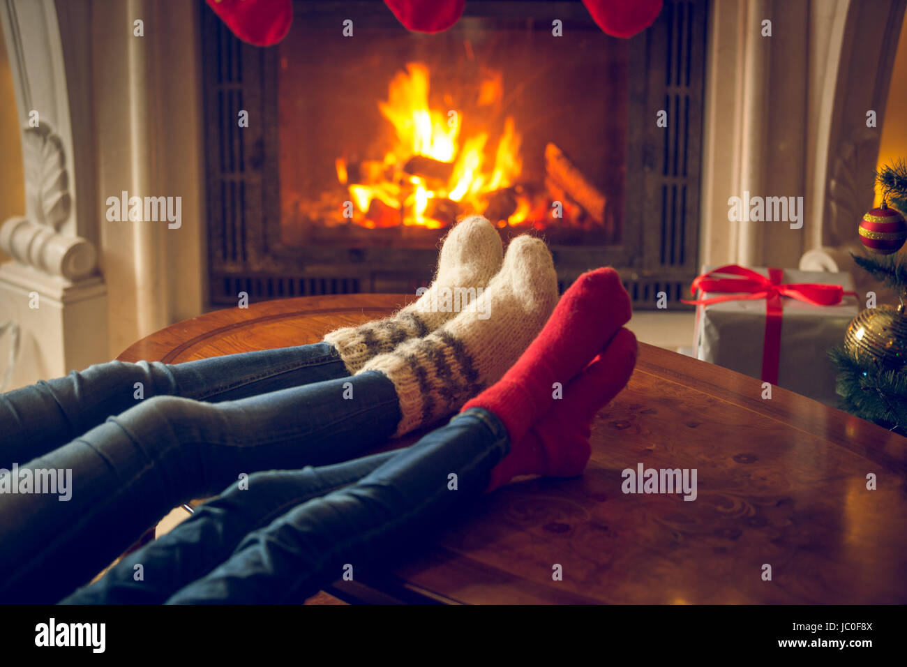 Closeup getönten Bild weiblicher und und Füße in Wolle Socken am Kamin im Chalet Erwärmung Stockfoto