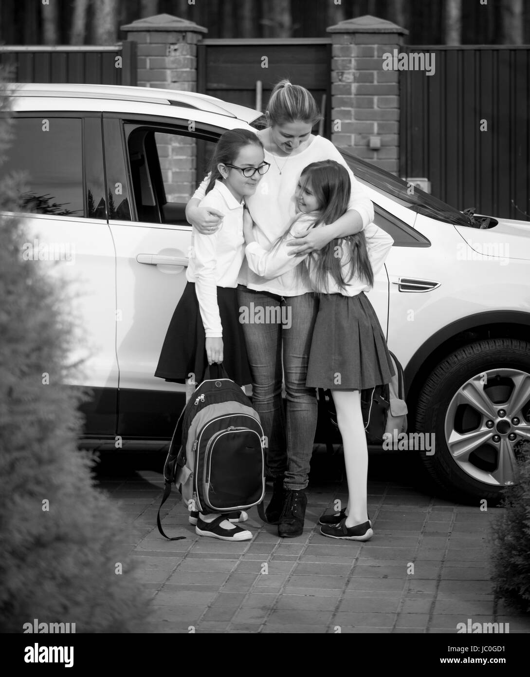Schwarz / weiß Foto der glücklichen Mutter umarmt Töchter nach der Schule Stockfoto