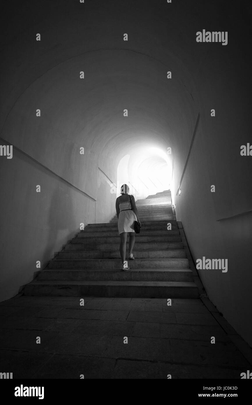 Monochrom Schoß Frau im Tunnel mit Licht am Ende der Treppe hinauf Stockfoto