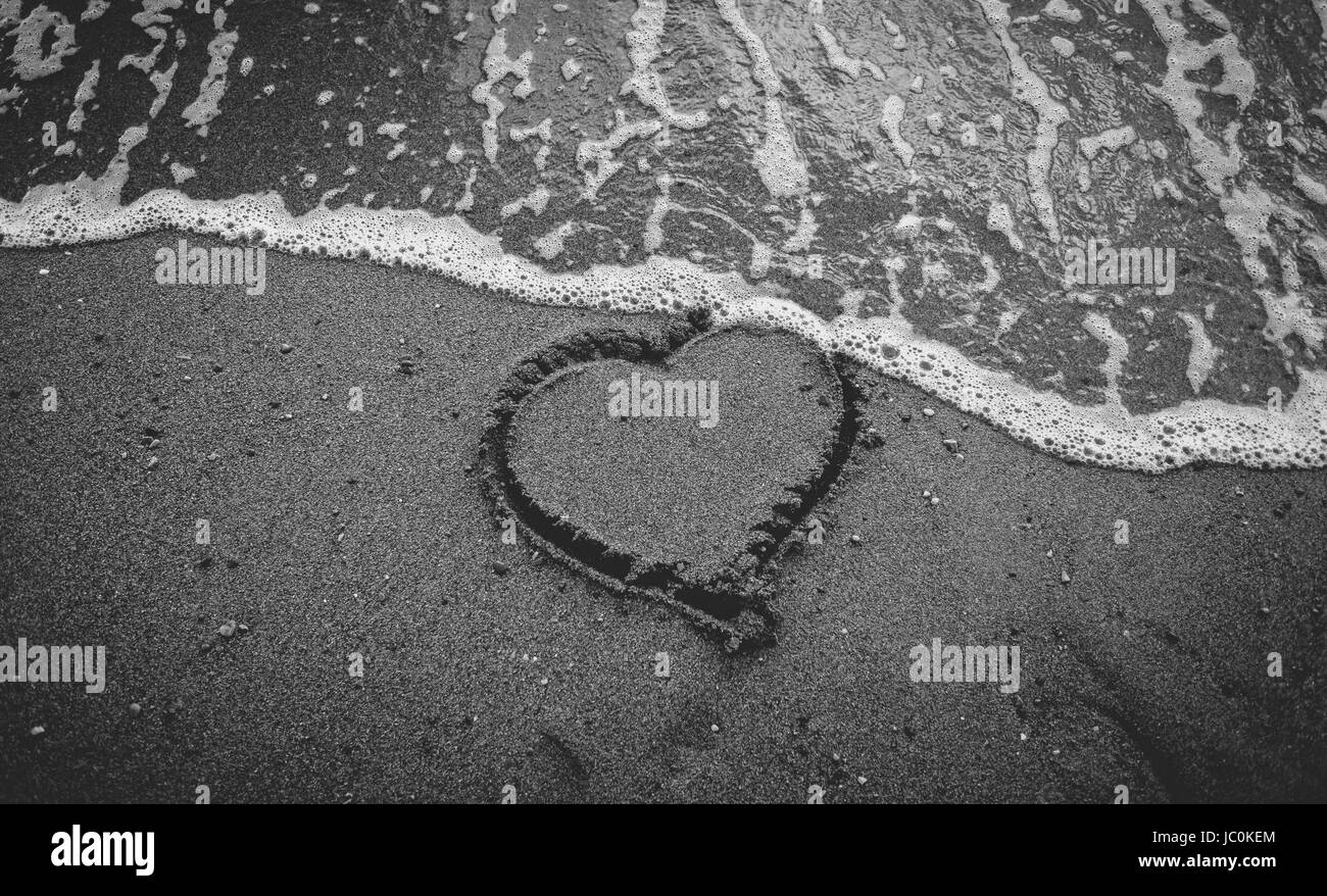 Schwarz / weiß Foto der Flutwelle weggespült Herz auf Sand gezeichnet Stockfoto