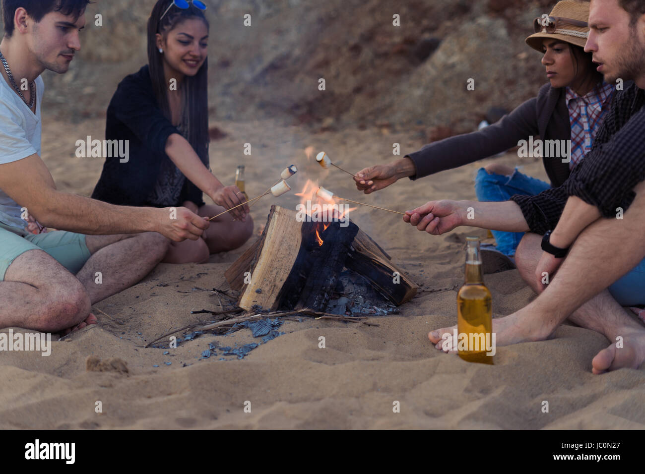 Freunde am wilden Strand zündete ein Feuer und Braten marshmallows Stockfoto