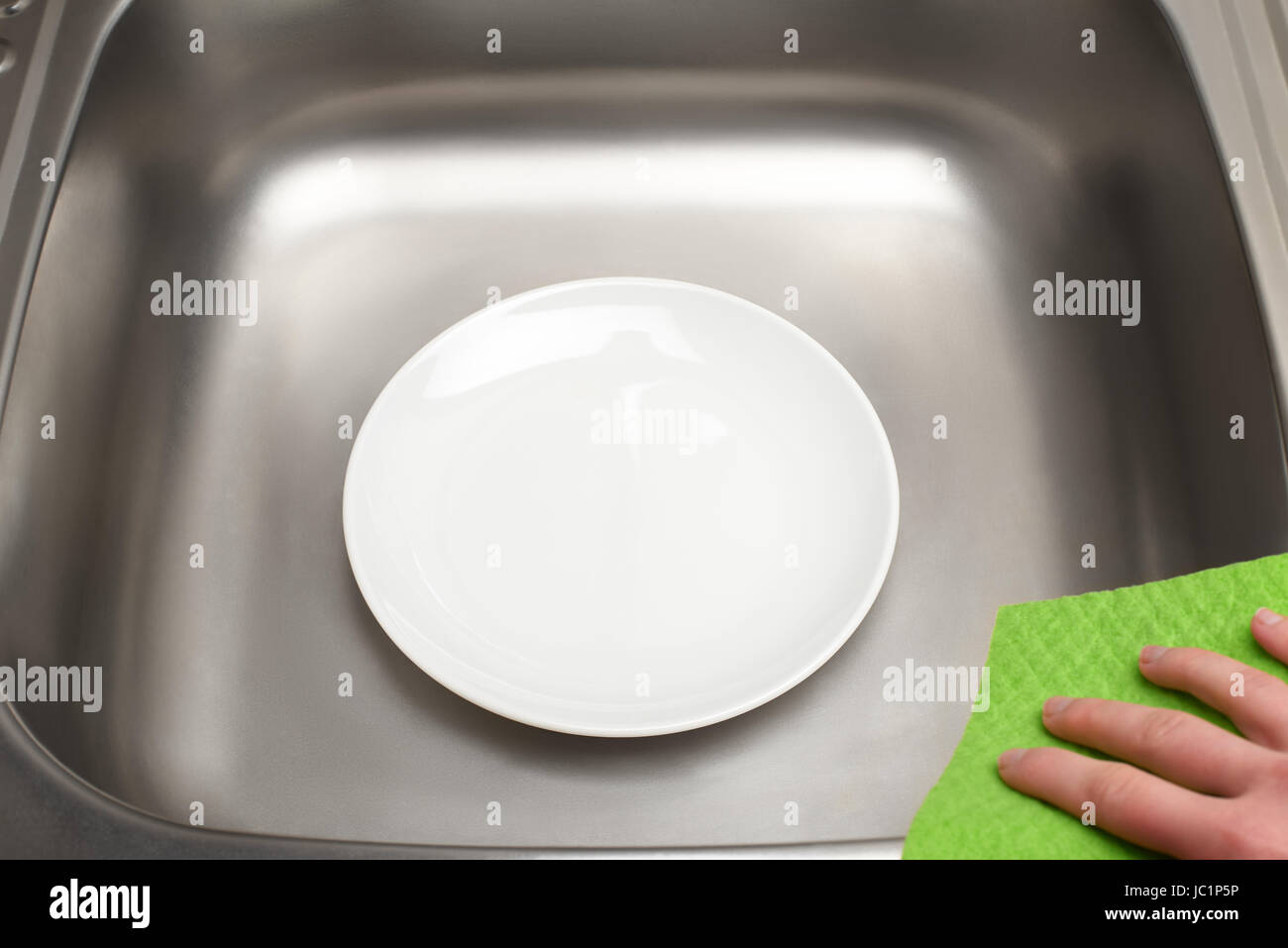 Nahaufnahme der Küchenspüle mit sauberen weißen Teller und grünes Tuch in weiblicher hand Stockfoto