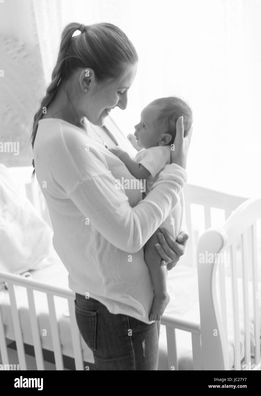 Schwarz-weiß-Porträt von schöne junge Mutter posiert mit ihrem Baby Kind Schlafzimmer Stockfoto