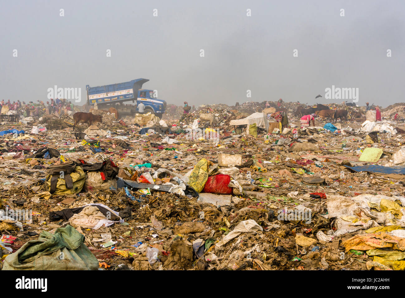 Ein Lkw beladen mit Müll ist das Fahren auf der staubigen dhapa Müllkippe, Arbeiter sind das Sammeln von wiederverwertbaren Materialien Stockfoto