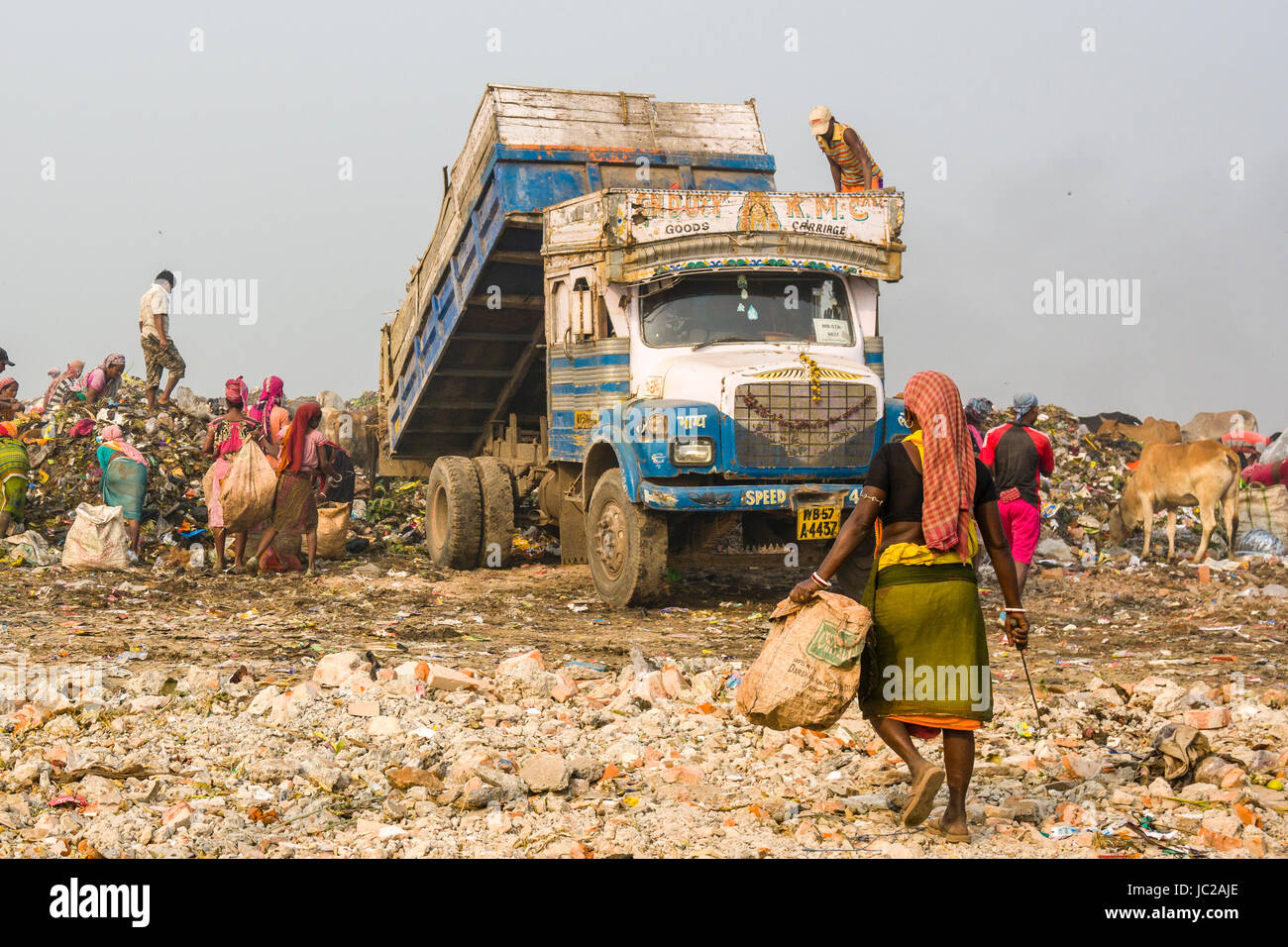 Ein Lkw beladen mit Müll abladen Auf staubigen dhapa Müllkippe, Arbeiter sind das Sammeln von wiederverwertbaren Materialien Stockfoto
