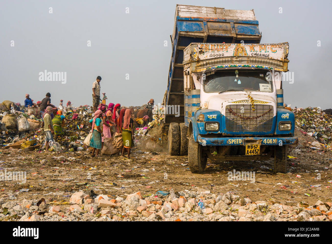 Ein Lkw beladen mit Müll abladen Auf staubigen dhapa Müllkippe, Arbeiter sind das Sammeln von wiederverwertbaren Materialien Stockfoto