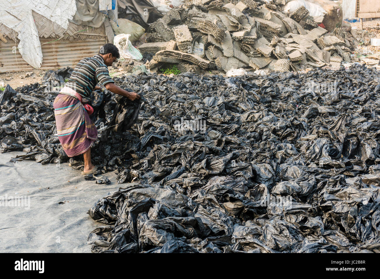 Ein Mann ist Sortieren aus wiederverwertbaren Kunststoffen in dhapa Müllhalde Stockfoto