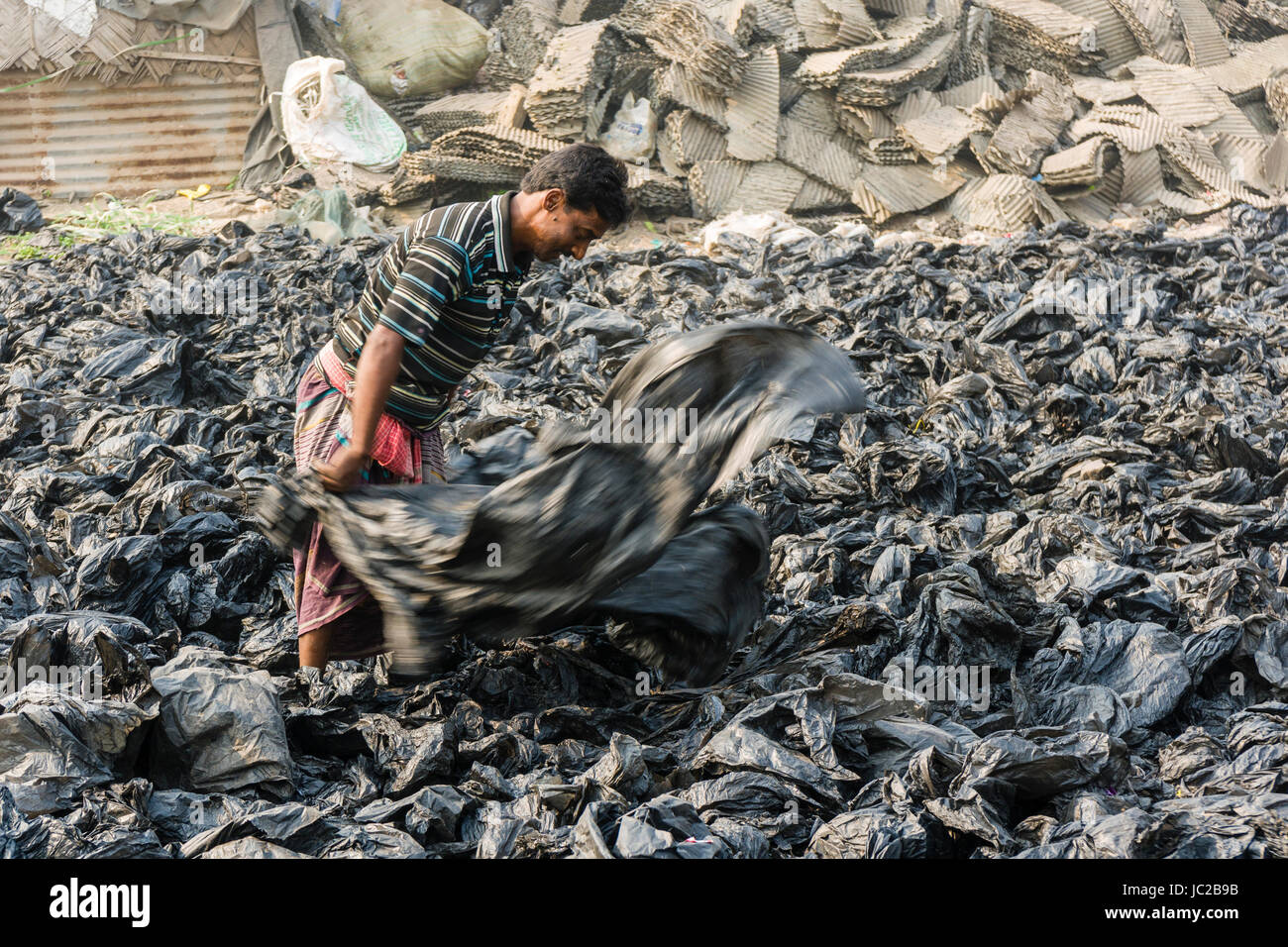 Ein Mann ist Sortieren aus wiederverwertbaren Kunststoffen in dhapa Müllhalde Stockfoto