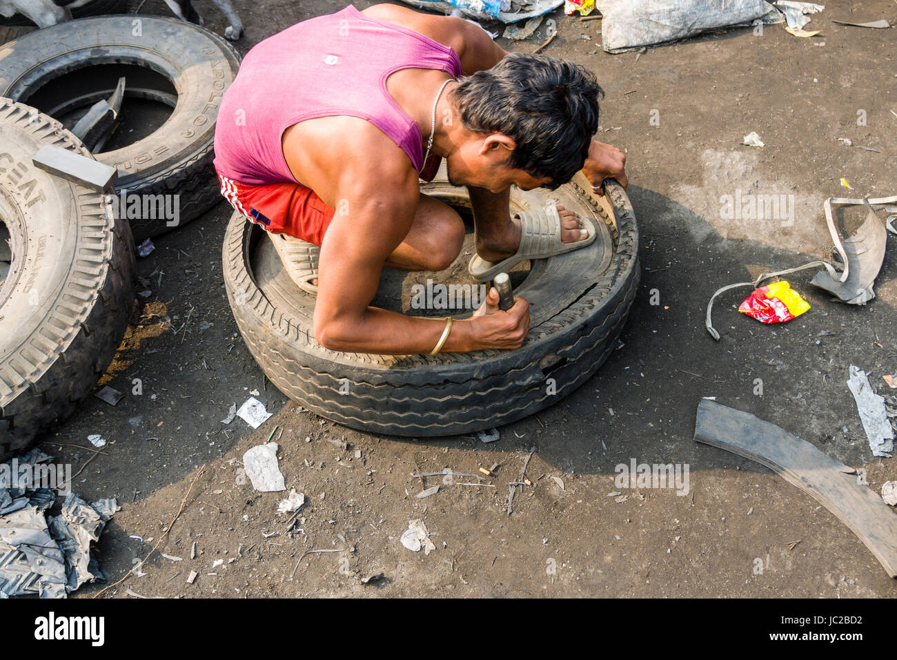 Ein Mann ist recycelbar Gummimaterialien von LKW-Reifen in dhapa Müllhalde Stockfoto