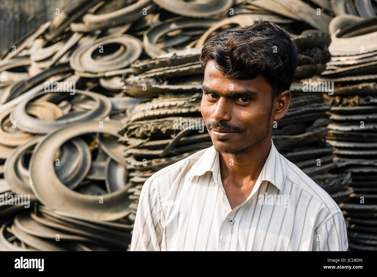 Porträt eines Mannes, Schneiden von wiederverwertbaren Materialien aus Gummi von LKW-Reifen in dhapa Müllhalde Stockfoto
