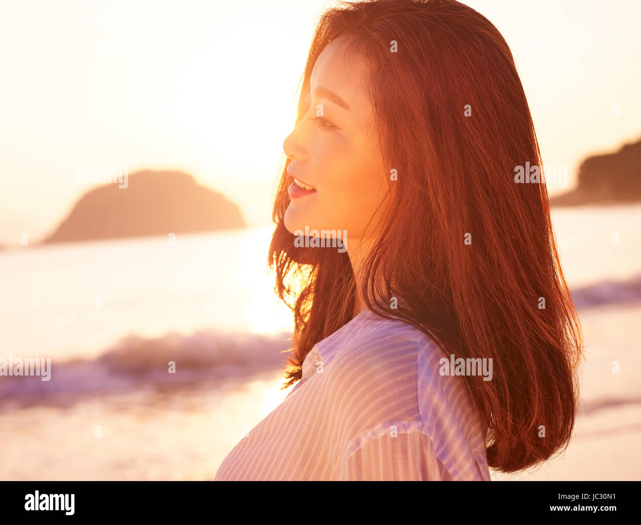 junge asiatische Frau, die das Sonnenlicht am frühen Morgen am Strand zu genießen. Stockfoto