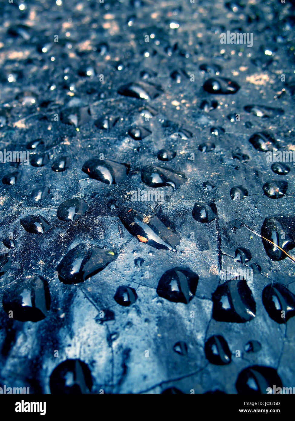 Transparente Wassertropfen auf dunkelblauem geknackt. Stockfoto