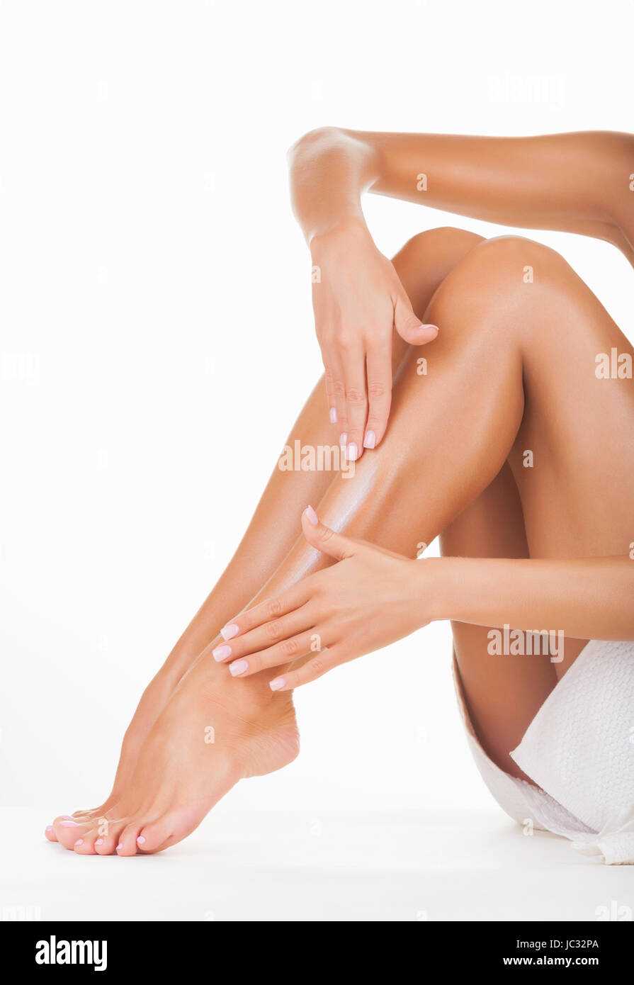 Auftragen der Feuchtigkeitscreme Creme an den Beinen isoliert auf weißem Hintergrund Stockfoto