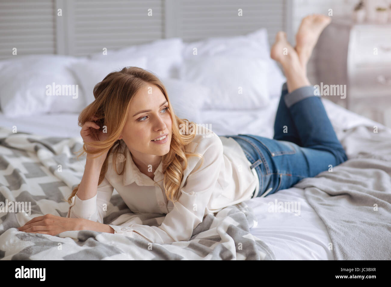Schöne junge Frau auf dem Bett liegend Stockfoto