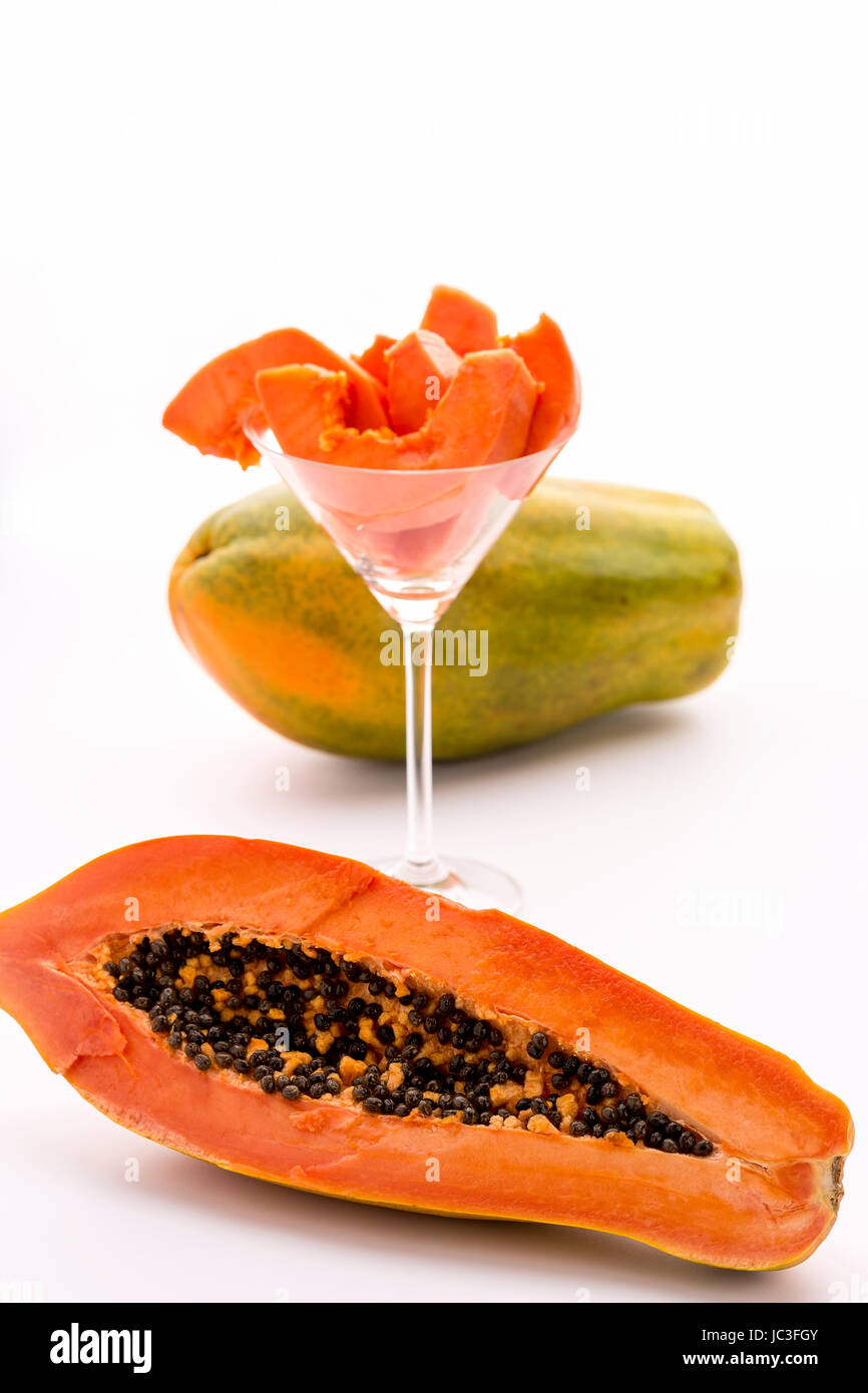 Eine Papaya-Frucht im Längsschnitt, seine sortiert in ein Cocktailglas und eine ganze Frucht Fruchtfleisch. Stockfoto