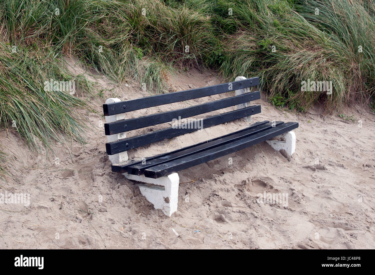 Sitzbank mit Sand aus der Winterstürme in Irland bedeckt Stockfoto