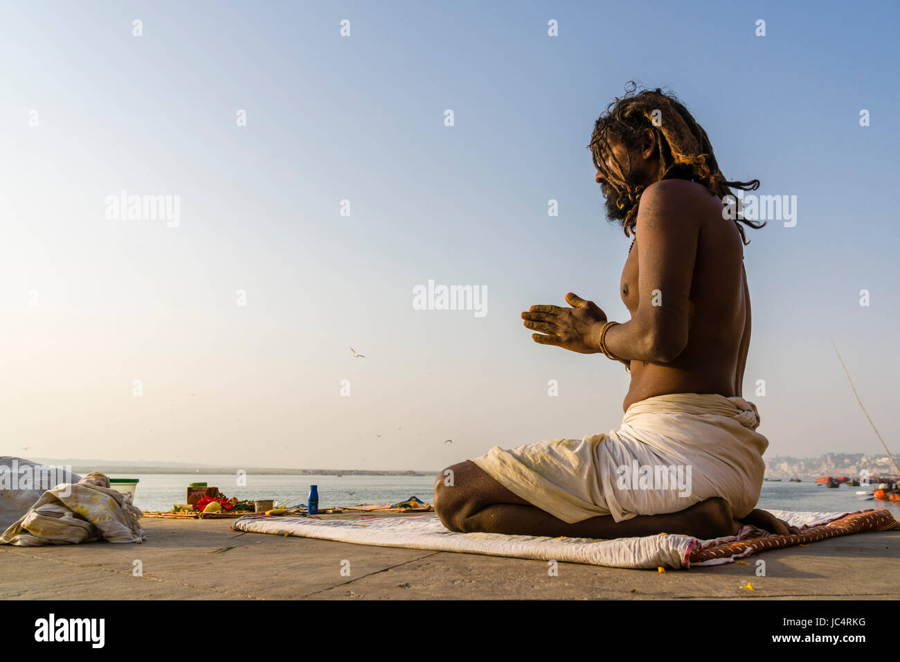 Ein sadhu, heiliger Mann, sitzt und Beten auf einer Plattform am heiligen Fluss Ganges Meer Ghat im Vorort godowlia Stockfoto