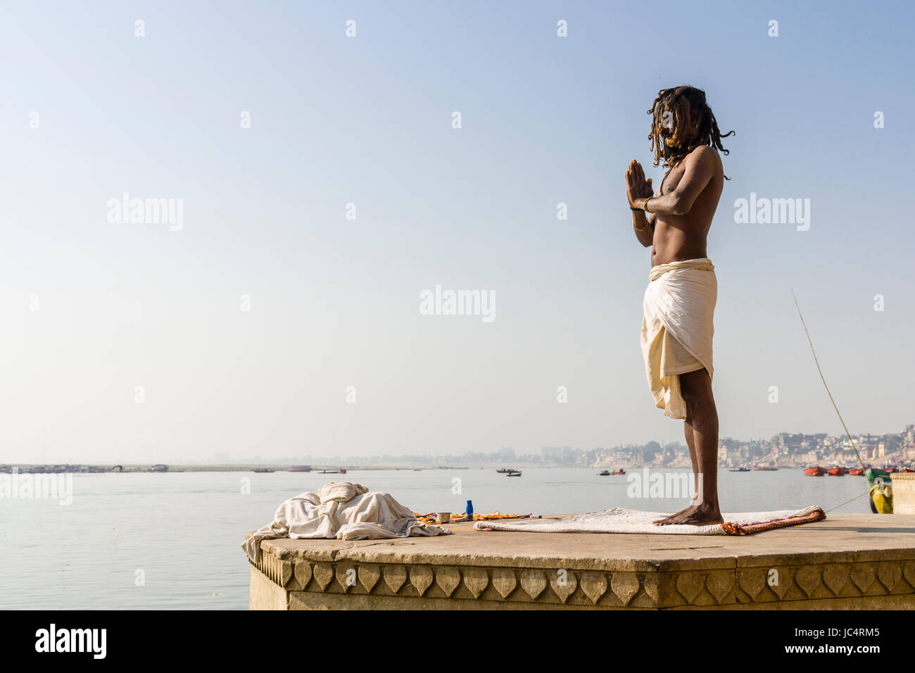 Ein sadhu, heiliger Mann, steht und Beten auf einer Plattform am heiligen Fluss Ganges Meer Ghat im Vorort godowlia Stockfoto
