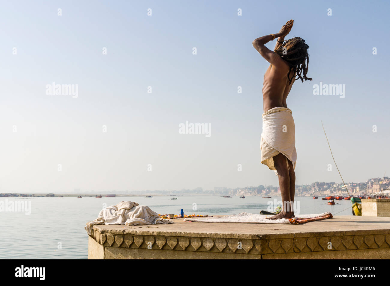 Ein sadhu, heiliger Mann, steht und Beten auf einer Plattform am heiligen Fluss Ganges Meer Ghat im Vorort godowlia Stockfoto