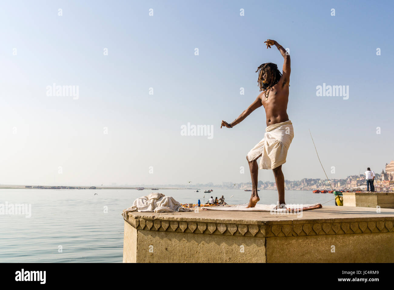 Ein sadhu, heiliger Mann, tanzt auf einer Plattform am heiligen Fluss Ganges Meer Ghat im Vorort godowlia Stockfoto