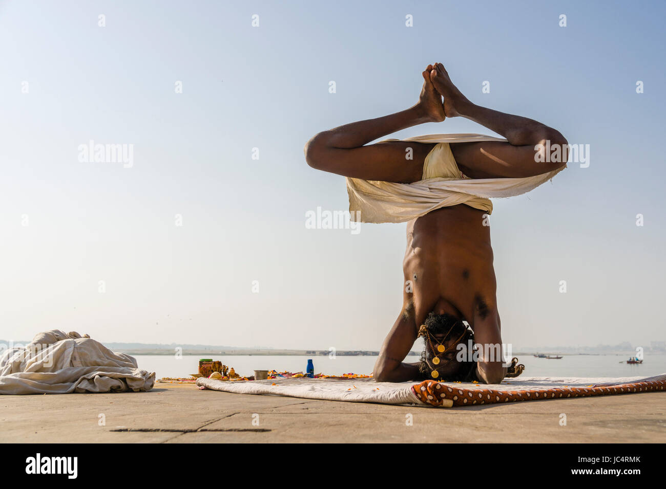 Ein sadhu, heiliger Mann, ist das Üben von Yoga Asana auf einer Plattform am heiligen Fluss Ganges Meer Ghat im Vorort godowlia Stockfoto