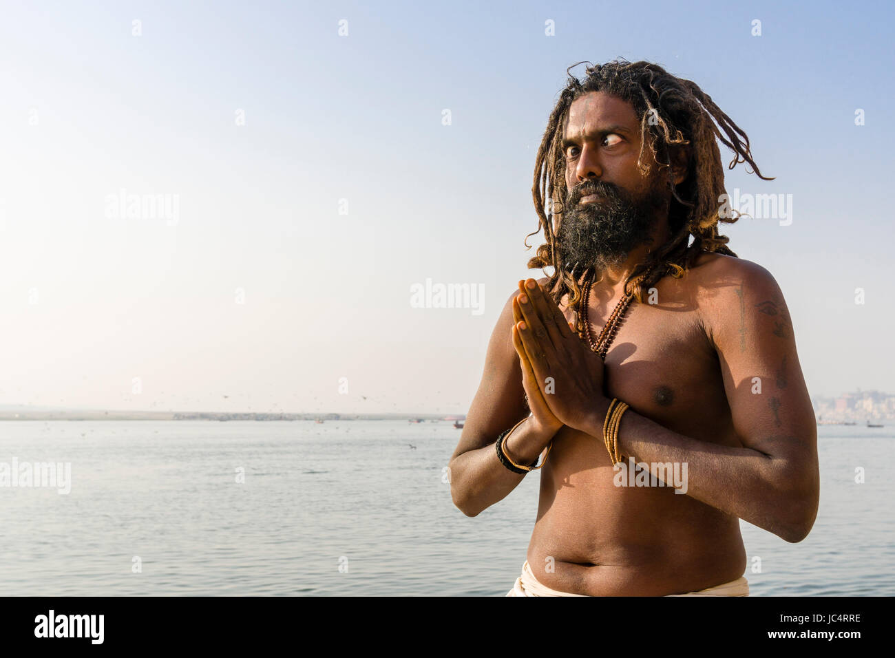 Ein Sadhu, Heiliger Mann, übt Auge Yoga Asana auf einer Plattform am heiligen Fluss Ganges Meer Ghat im Vorort Godowlia Stockfoto