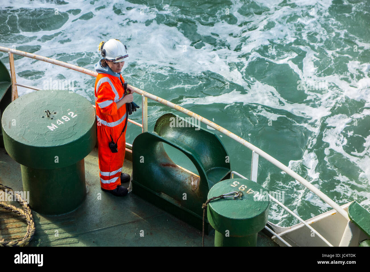 Weibliches Besatzungsmitglied in Orange insgesamt und tragen Schutzhelm arbeiten an Deck von Autotransporter / Cargo Schiff auf hoher See Stockfoto