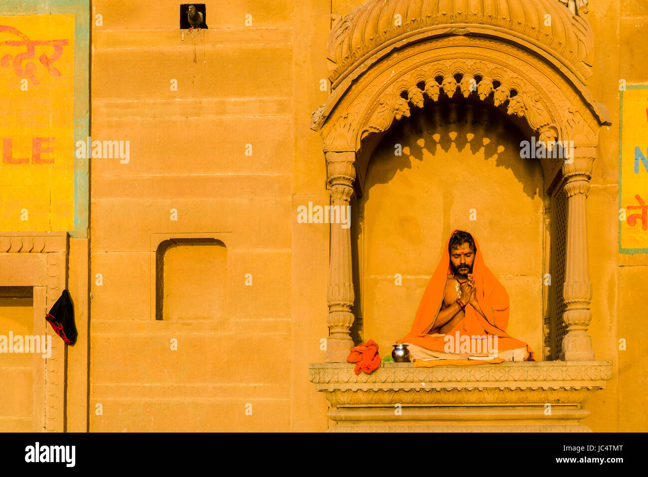 Ein Priester, Brahmane, sitzt und betend auf einem Balkon am heiligen Fluss Ganges Lalita Ghat im Vorort Godowlia Stockfoto