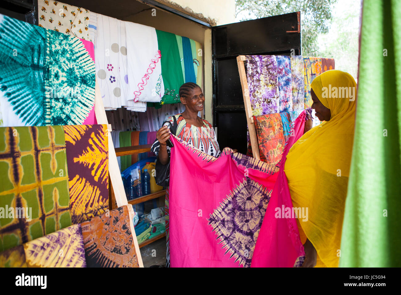 Salma likupila (rechts) im Gespräch mit einem Kunden in Ihren Shop ein weiblicher Small Business batik Shop Besitzer mit einem Kunden, Tansania, Afrika. Stockfoto