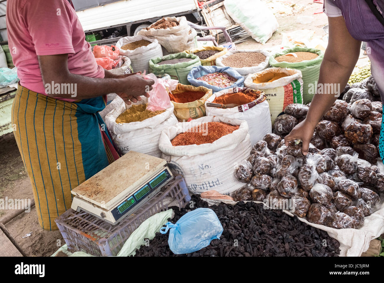 Ein Kunde sieht durch Gewürze auf einen Stand auf einem freien Markt in Negombo, Sri Lanka Stockfoto