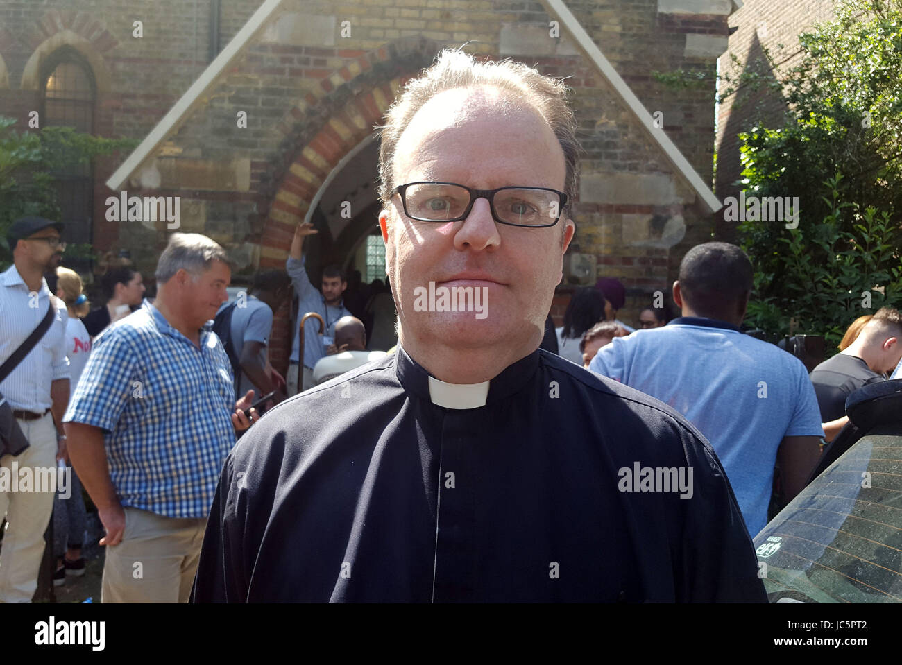 Reverend Mark O'Donoghue, der Bereich Dekan von Kensington, steht außerhalb St Clement und St James Church ist seit 03:30 Menschen evakuiert worden, nachdem ein Feuer der 24-geschossige Grenfell Turm im Westen Londons verschlungen. Stockfoto