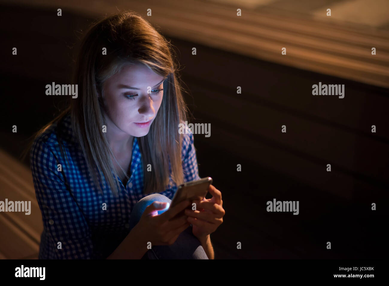 Verärgert unglücklich Frau mit Handy auf graue Wand Hintergrund isoliert. Traurig aussehende Mädchen SMS auf smartphone Stockfoto