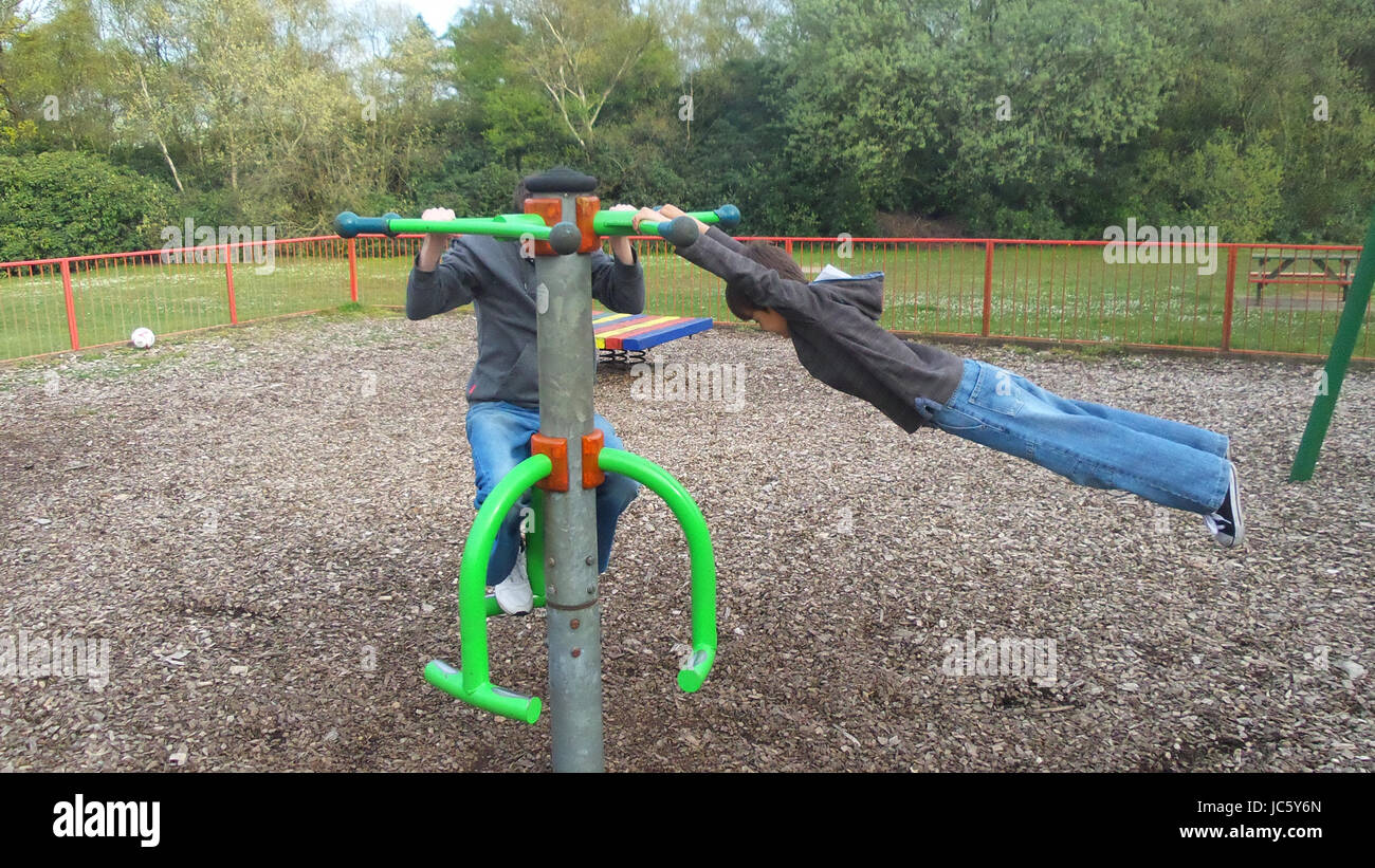 Junge Spinnen auf Spielplatz Spinner und schwingen sich horizontal während hängen mit seinen Händen Stockfoto