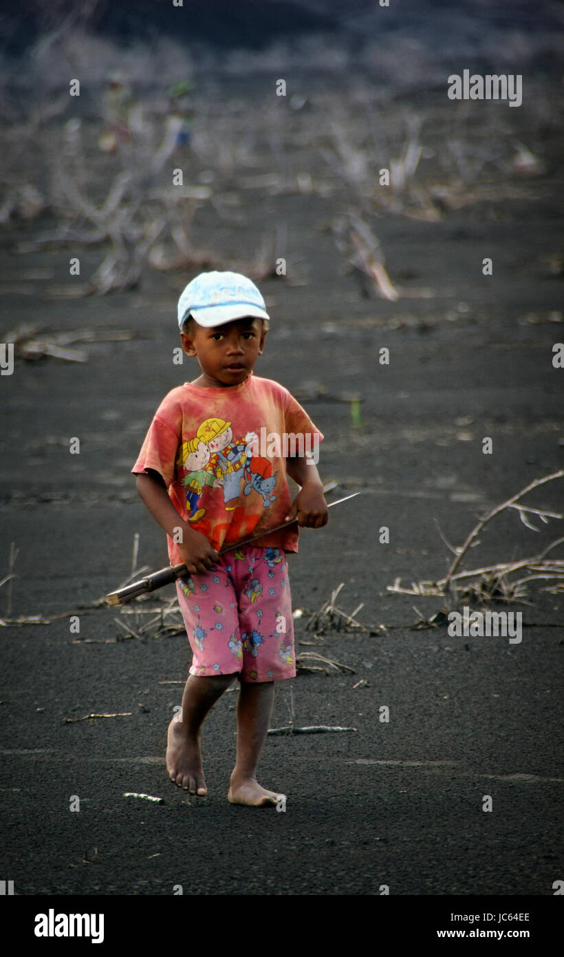 Ein kleiner Junge trägt eine Machete über die Asche hinterließ Tavurvur Vulkan Mt. in der Nähe von Rabaul, Papua-Neu-Guinea. Die meisten der einheimischen ausgezogen, aber einige noch Stockfoto