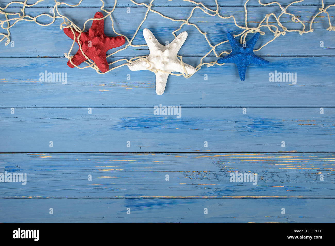 patriotischen roten weißen und blauen Seestern mit nautischen Netz auf rustikalen blau Holz Stockfoto