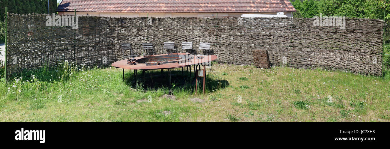 Die ländlichen Zaun aus trockenem Schilf umgibt den verlassenen Ort für einen Grill braten. Rostiges Metall Feuerschale und faule Stühle. Panorama Collage aus se Stockfoto