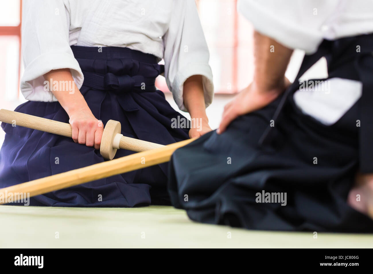 Mann und Frau im Kampf mit Holzschwertern im Aikido-Training in der Kampfkunst-Schule Stockfoto