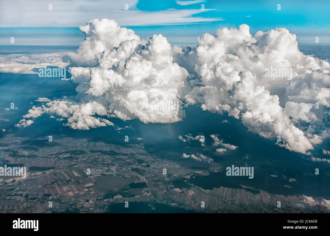 Blick auf Wolken und Land vom Flugzeugfenster aus großer Höhe. Stockfoto