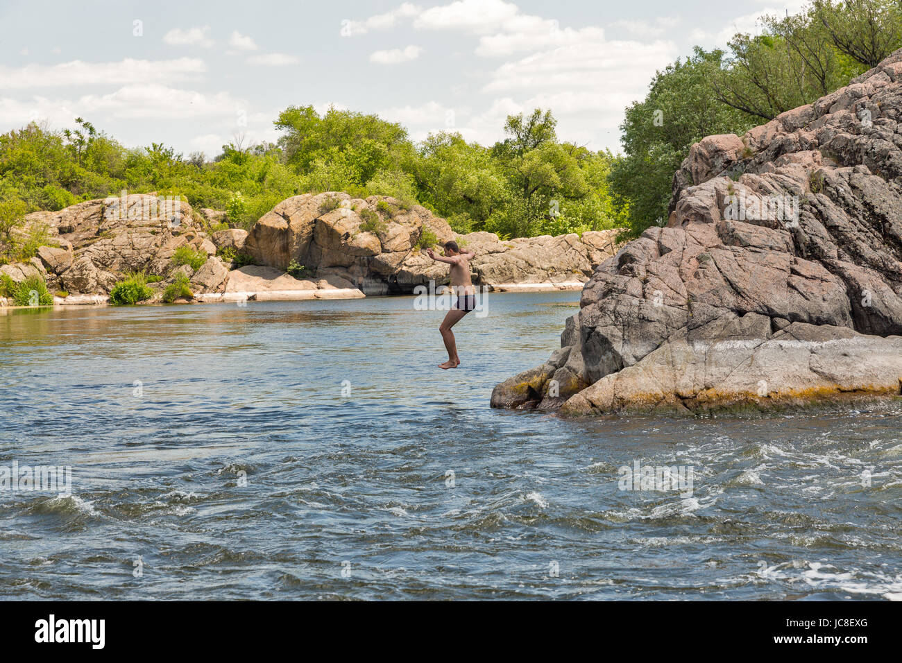 MIGEYA, UKRAINE - 1. Juni 2017: Unbekannte kaukasischen Jüngling springt in den Fluss Südlicher Bug in der Nähe von berühmten Roten Tor oder Integral Stromschnellen. Stockfoto