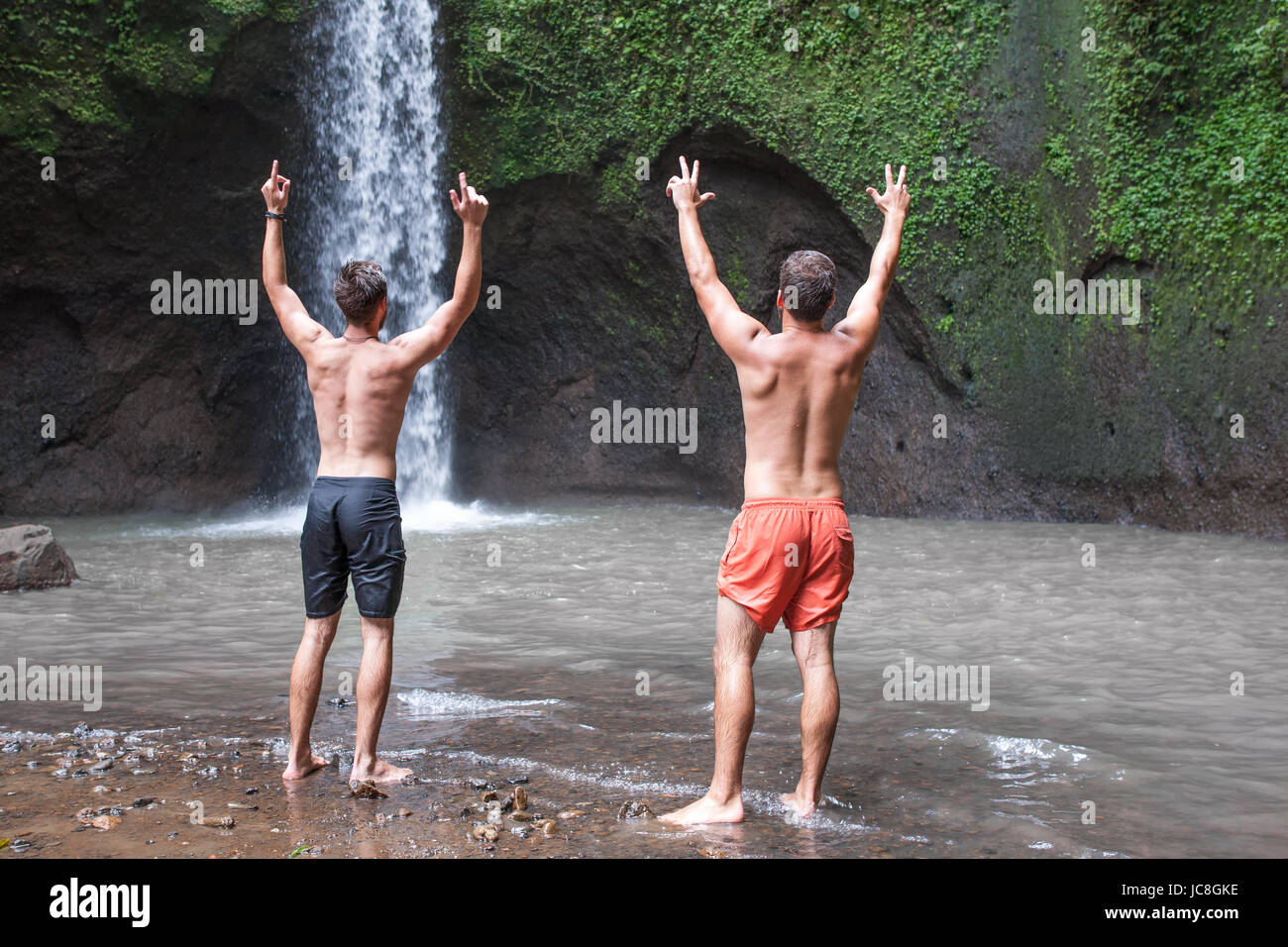 Zwei Männer mit Hände hoch. Bild der Natur und der schöne Tibumana Wasserfall in bali Stockfoto