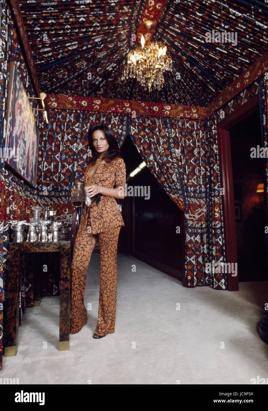Die belgisch-amerikanische Geschäftsfrau Diane von Fürstenberg in ihrer Wohnung der Park Avenue in New York. Sie posiert in der marokkanischen Stil Bar-Ecke, und sie trägt einen Safari braunen Anzug Shorty Blick (DVF-Label).  1975 Foto Michael Holtz Stockfoto