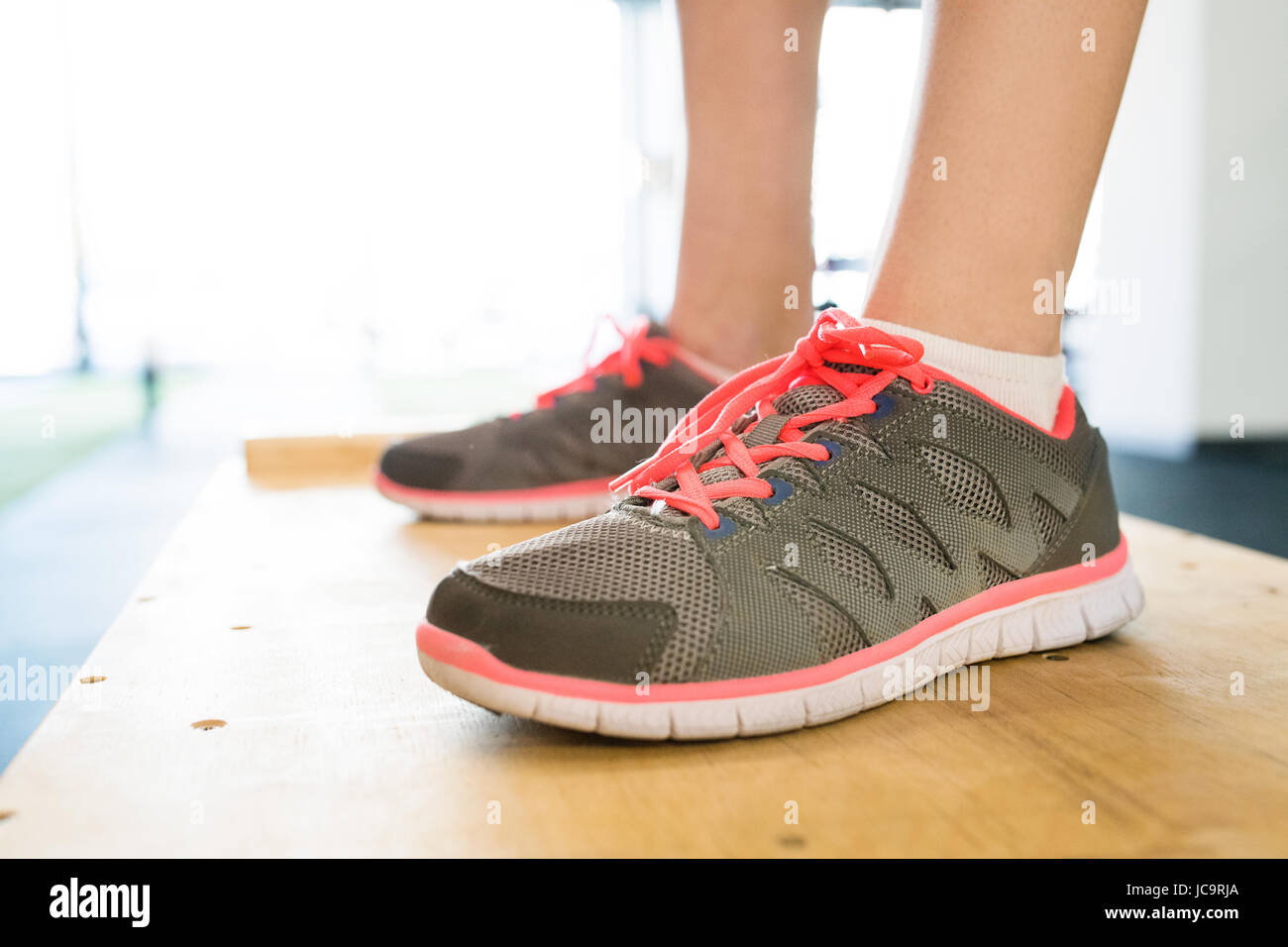 Füße der jungen Frau im Fitness-Studio stehen auf Holzkiste. Stockfoto