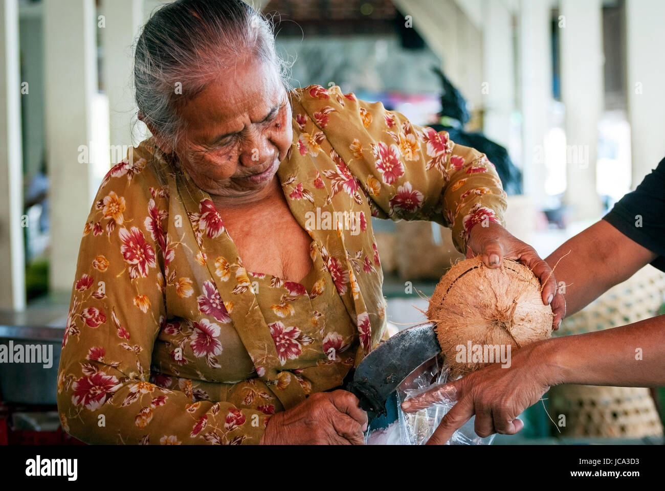 YOGYAKARTA, Indonesien - SEPTEMBER, 15: alte Frau Kokosnuss öffnen, die Kokosmilch auf dem lokalen Markt in Yogyakarta, Indonesien auf Septmber 15, 20 Stockfoto